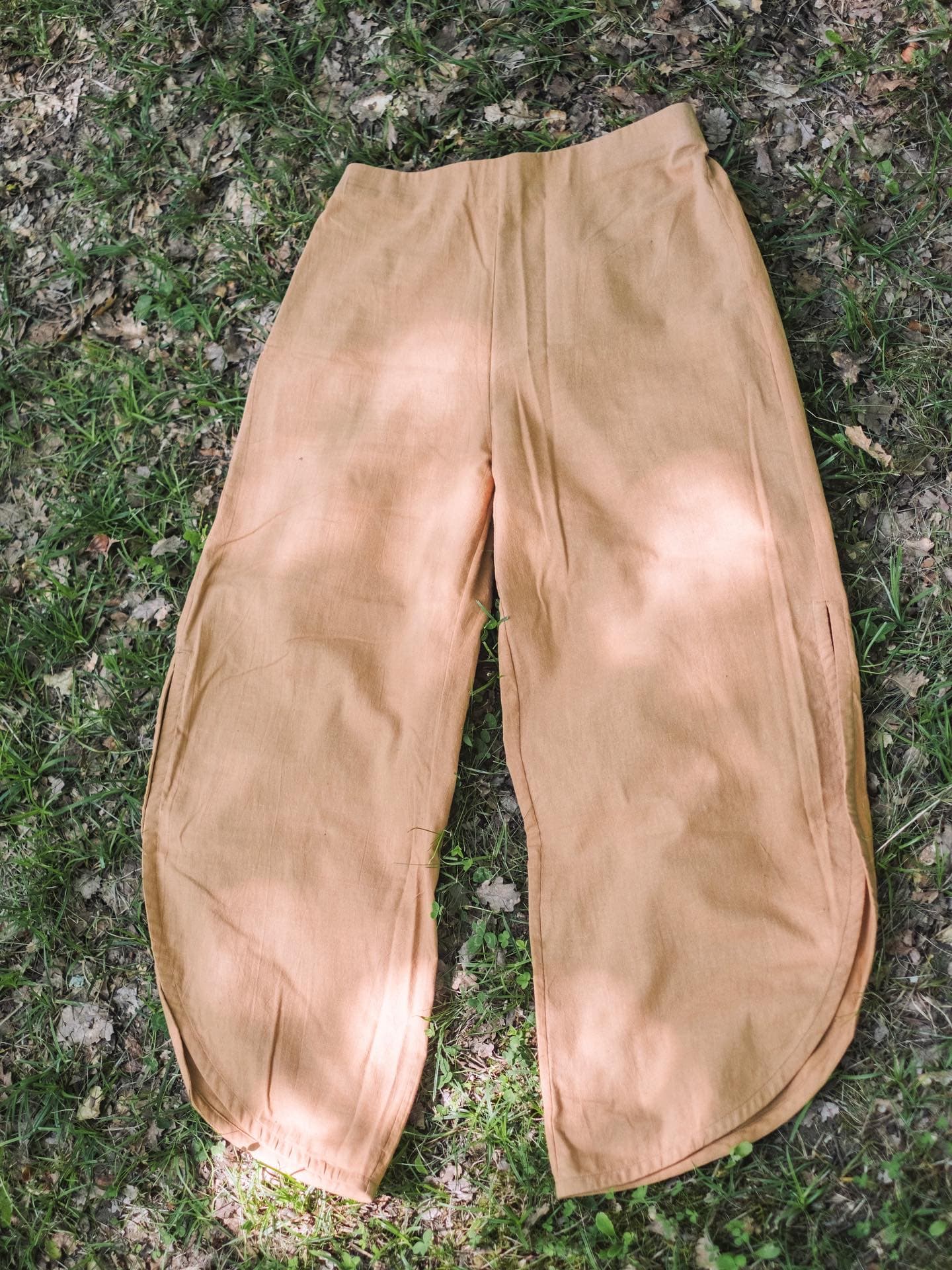 Ochre-dyed trousers laid flat on the grass